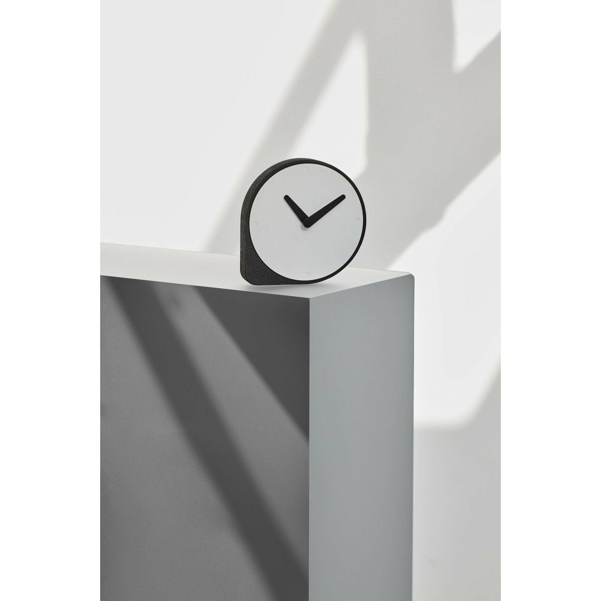 A Puik Clork Table Clock, Black sitting on top of an asymmetrical white box.