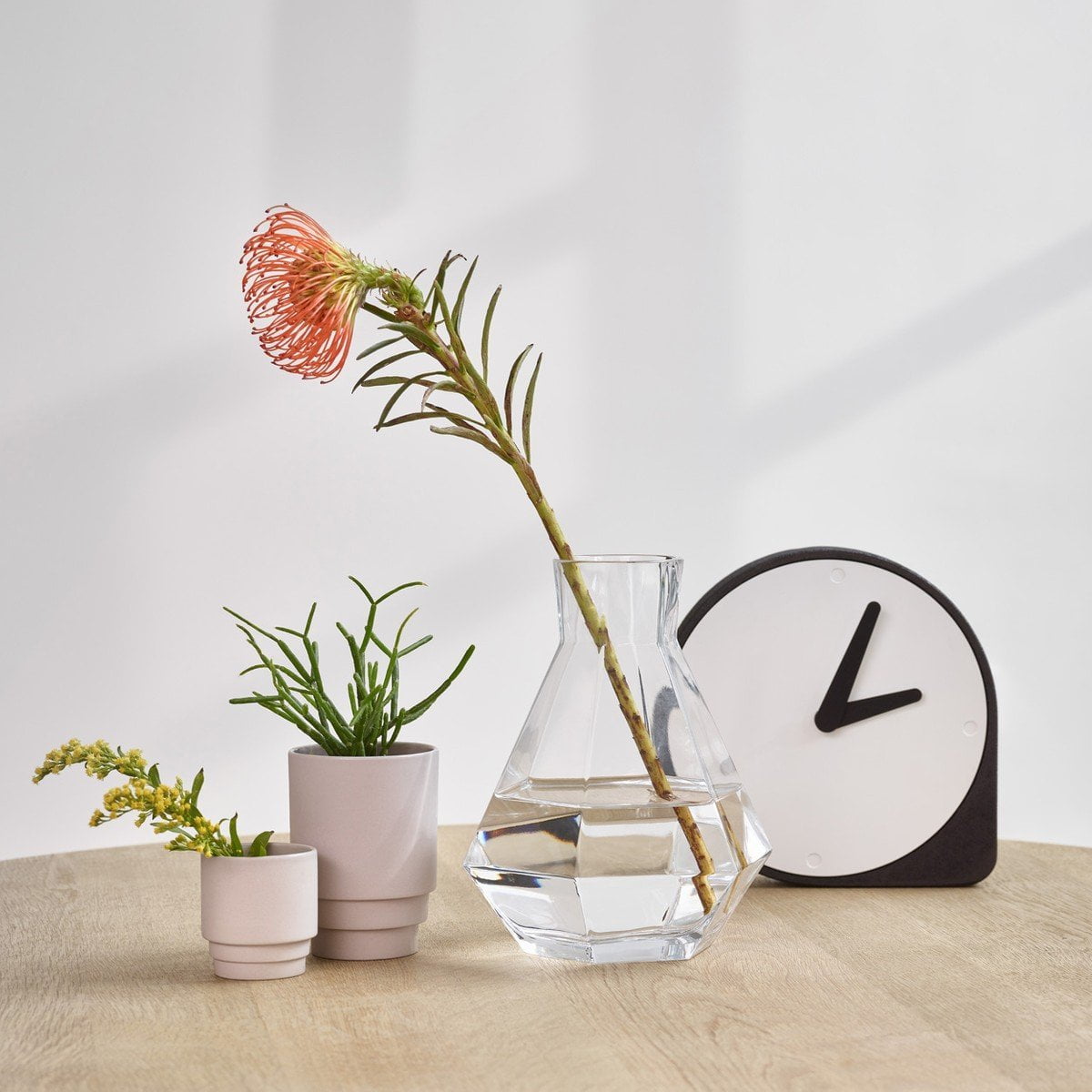 A black vase with a minimalist flower and a Puik Clork Table Clock, Black.